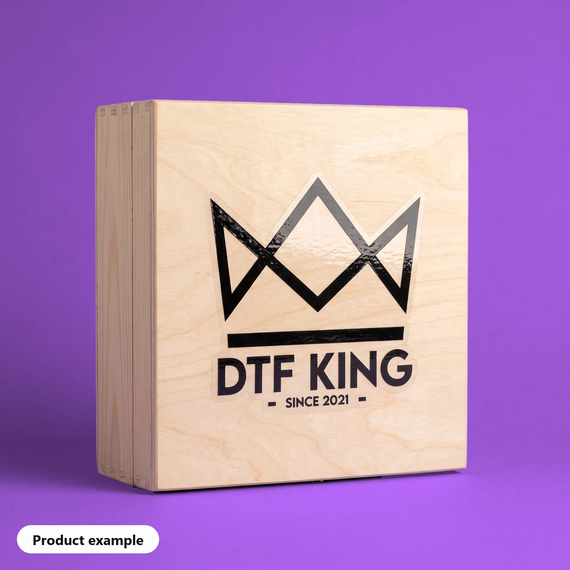 Contour-cut vinyl sticker on clear film, gloss laminated, with the DTF KING logo on a wooden box