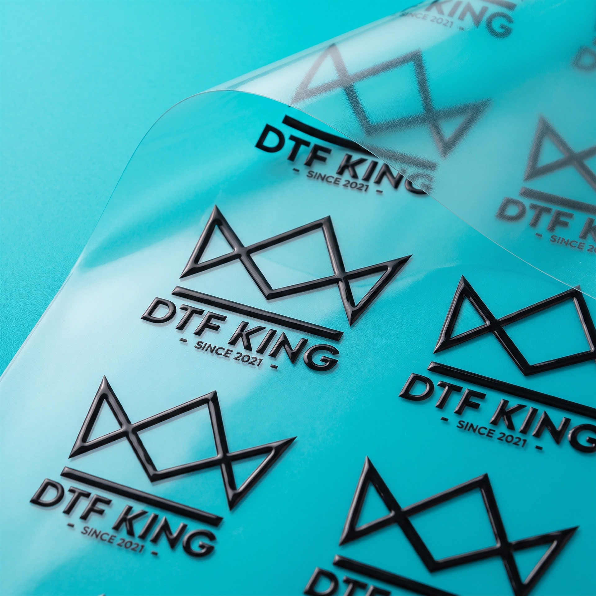 UV DTF Transfer glänzend von der Rolle mit DTF-King Logo vor türkisem Hintergrund