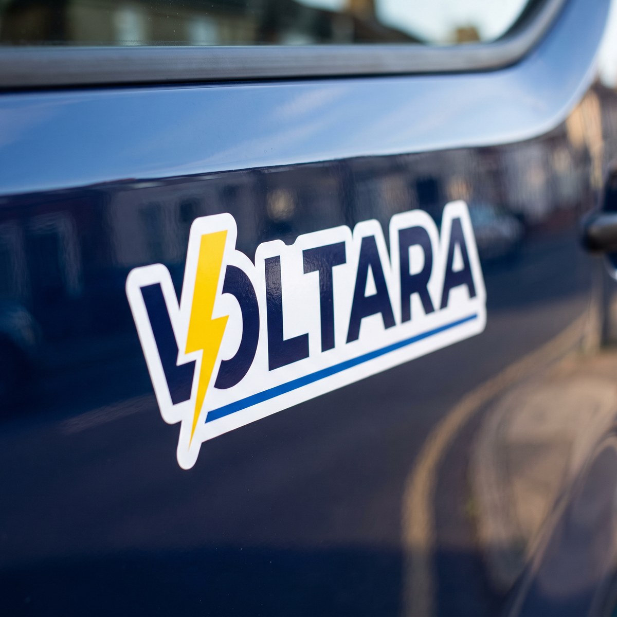 Konturgeschnittener Vinyl-Sticker auf weißer Folie mit dem Logo einer Beispielfirma auf der lackierten Seitenwand eines Transporters