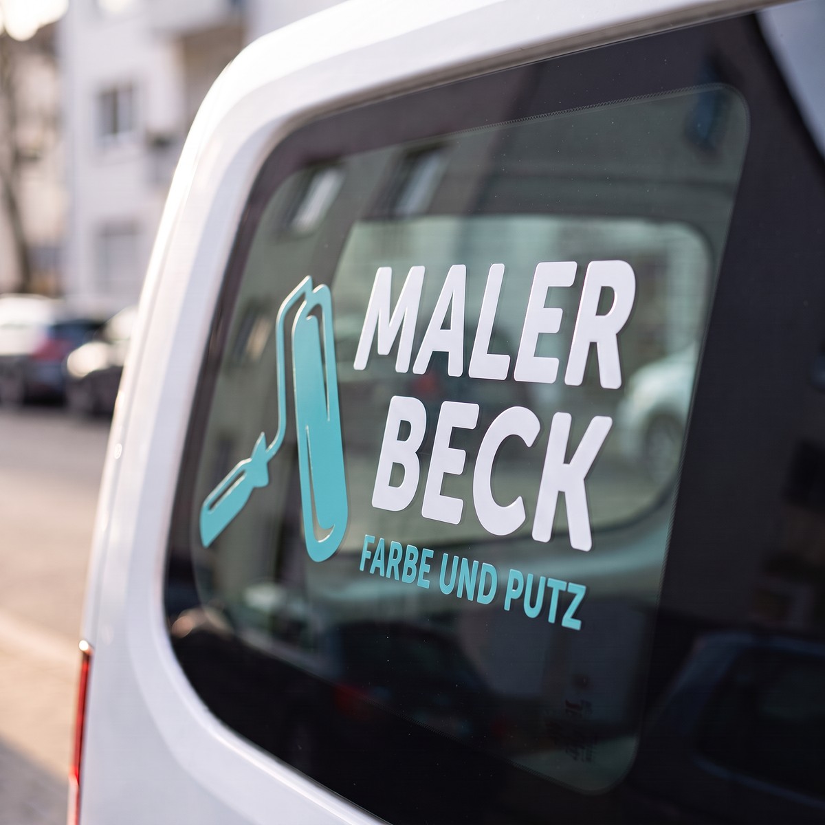 White vehicle with a UV DTF rub-on sticker on the side window, white lettering of a painting business with a turquoise paint roller