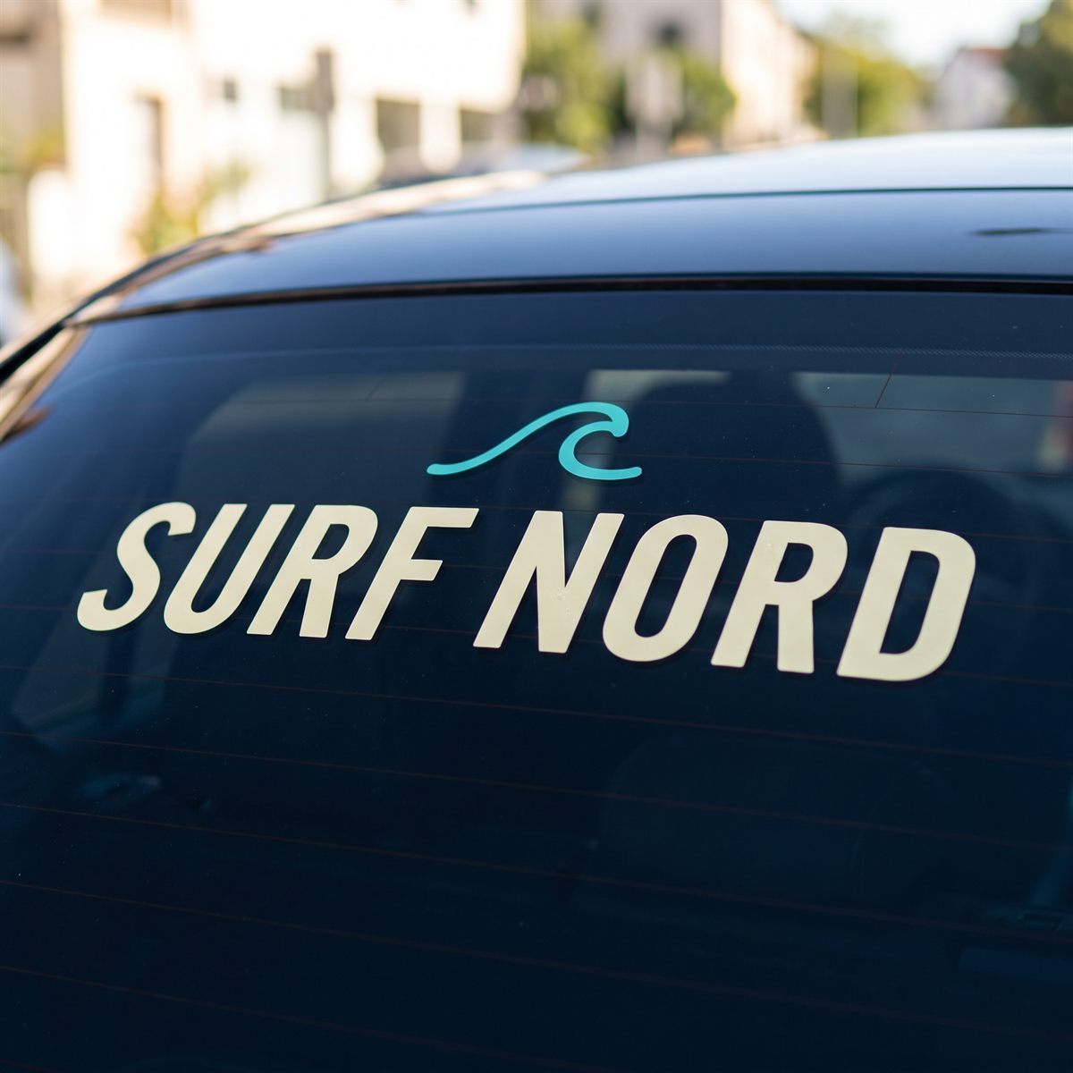 Tinted car window with a Standard UV DTF rub-on sticker, cream lettering