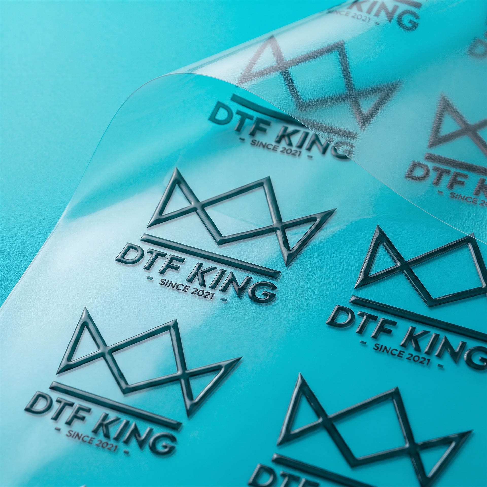 UV DTF Transfer transparent von der Rolle mit DTF-King Logo vor türkisem Hintergrund