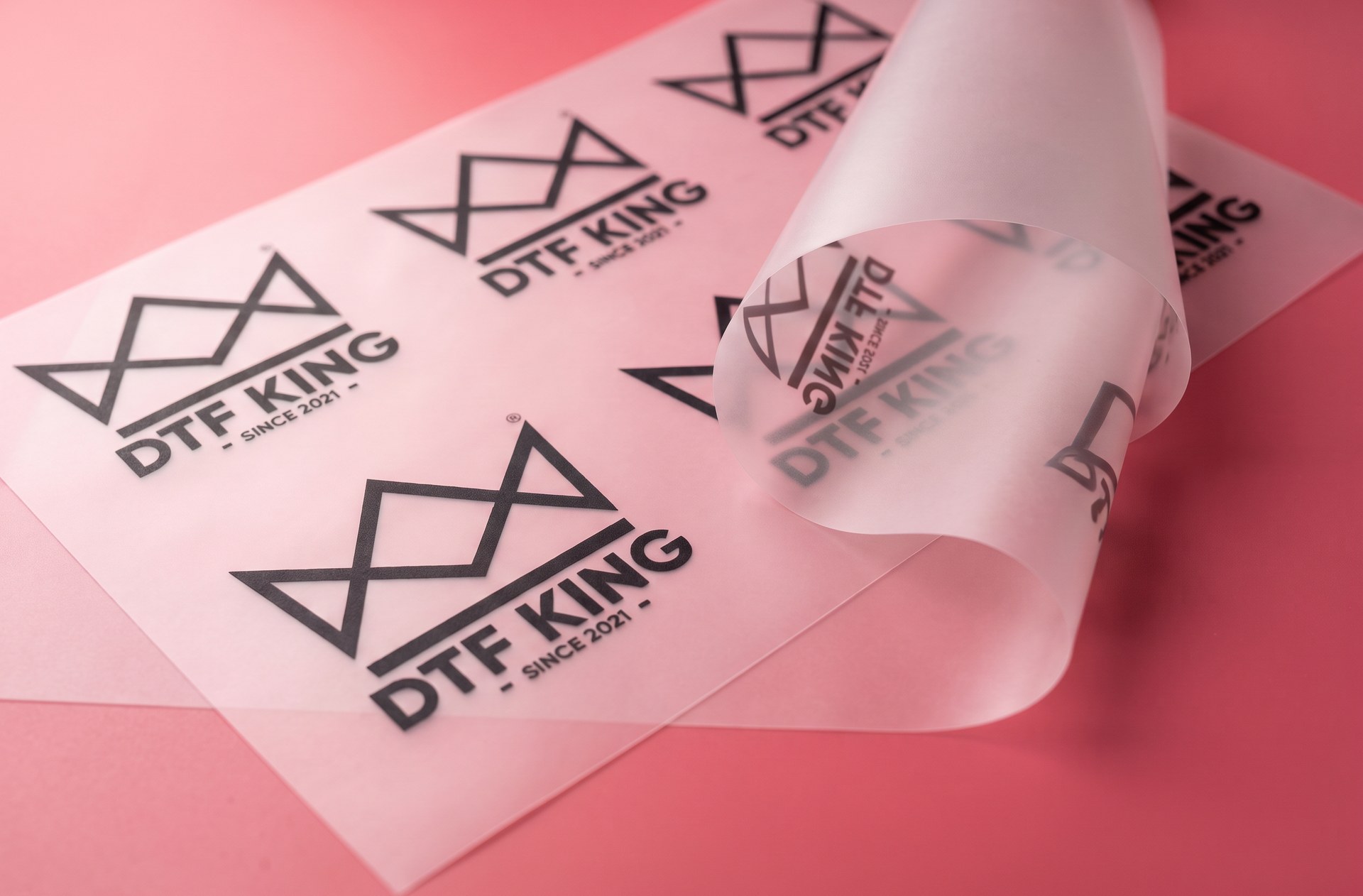 Printed DTF transfer film with DTF-King logos on a pink background